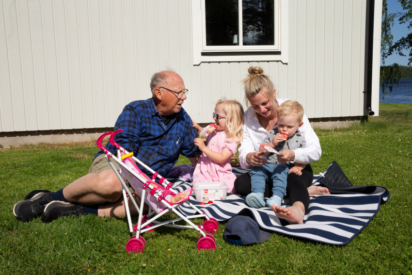 Familj med tre generationer på filt på gräset